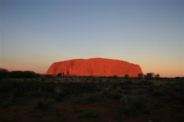 De majestueuze rode rots bij zonsondergang. Bewonder het, verbaas je, maar klim nliever niet.